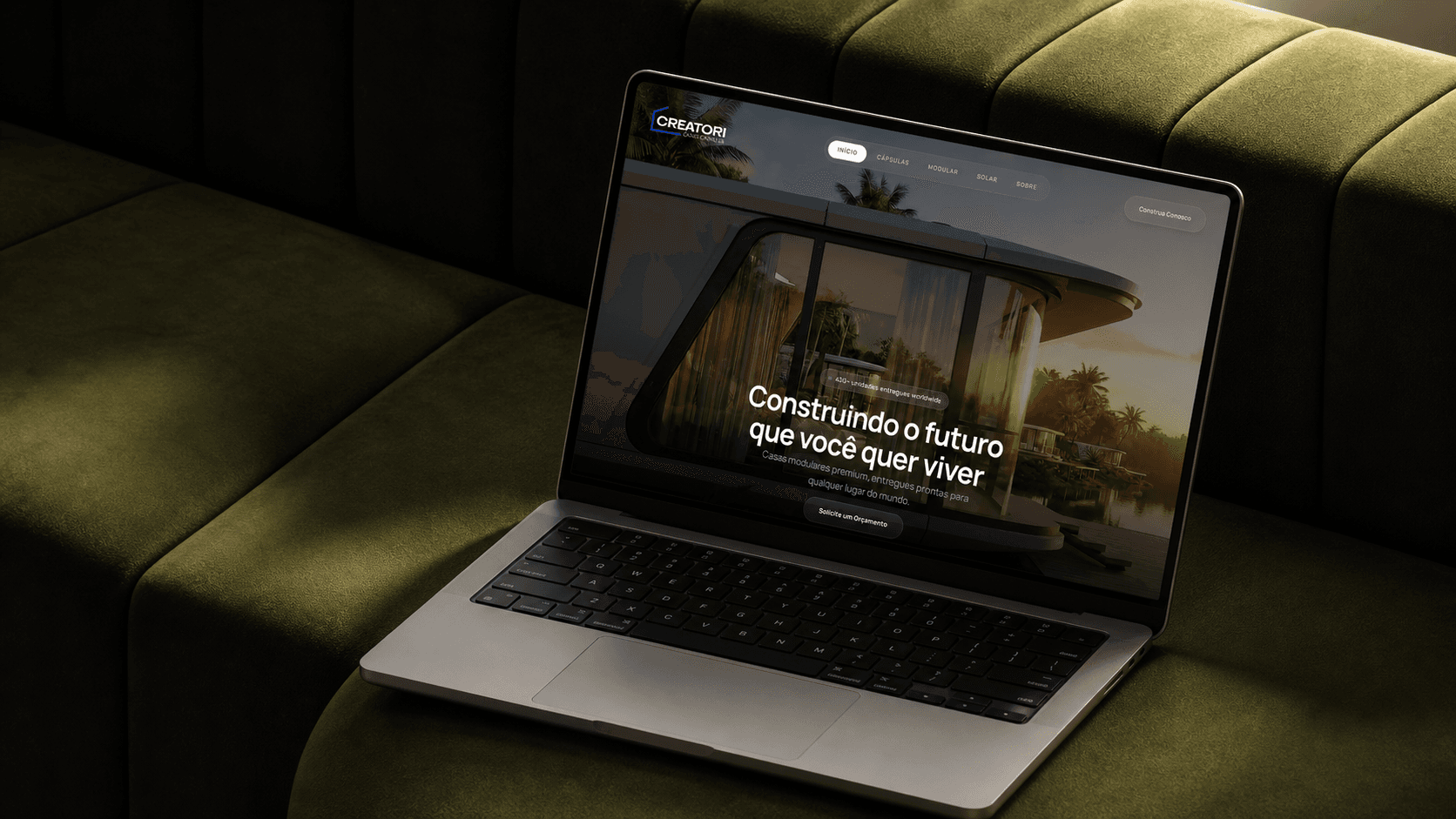 Website da Creatori em um MacBook sobre uma poltrona verde